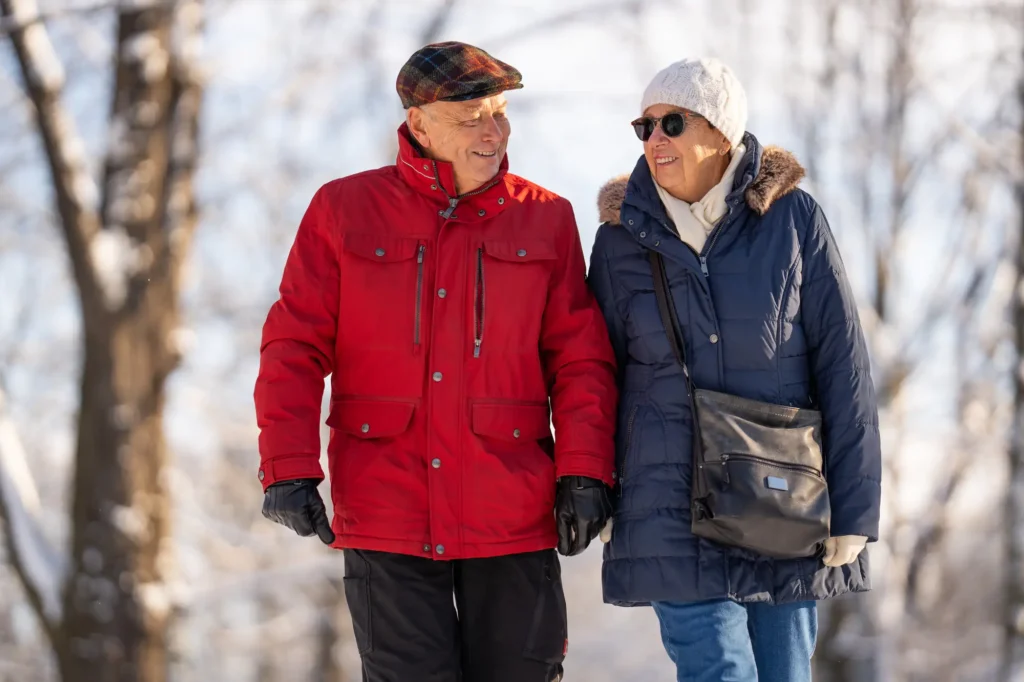 Older couple walking safely on a cleared winter path as part of winter safety tips for seniors