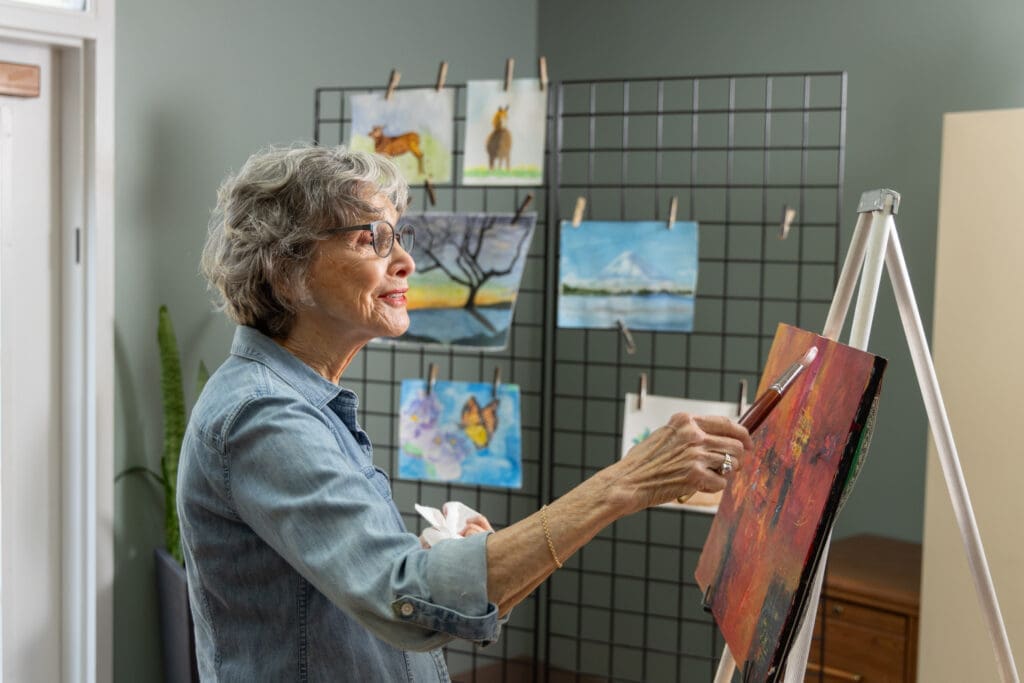 Older adult woman painting in art studio to practice mindfulness activities for seniors at Canterbury Woods Williamsville.